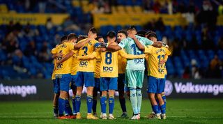 Las Palmas players in a huddle for a game against Mirandes in Spain's second tier in January 2023.