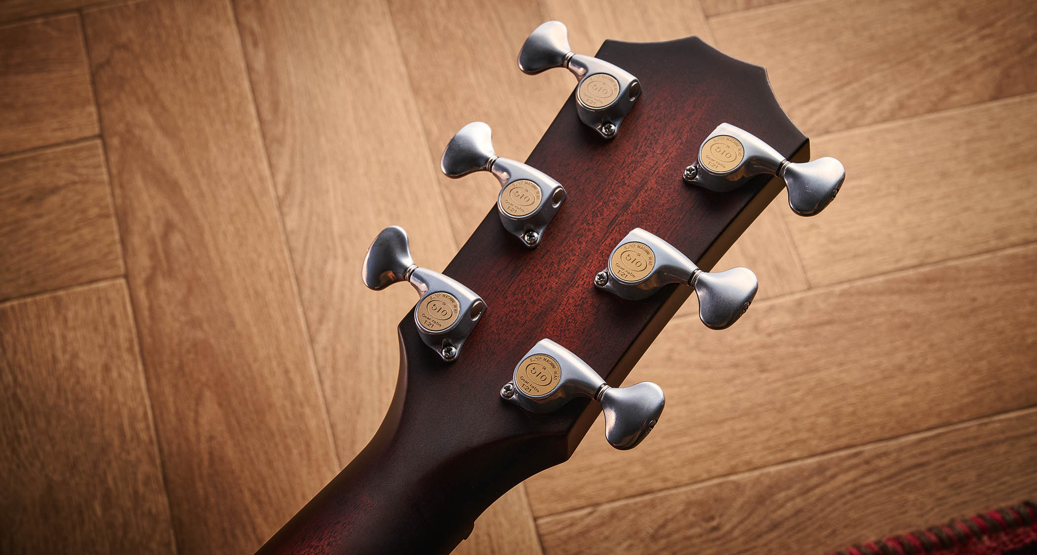 Taylor Builder’s Edition 514ce Kona Burst pictured against a wooden floor and patterned rug.