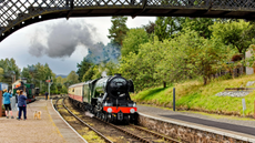 Flying Scotsman Steam Train at Boat of Garten Scotland with people on the platform as the train enters the station