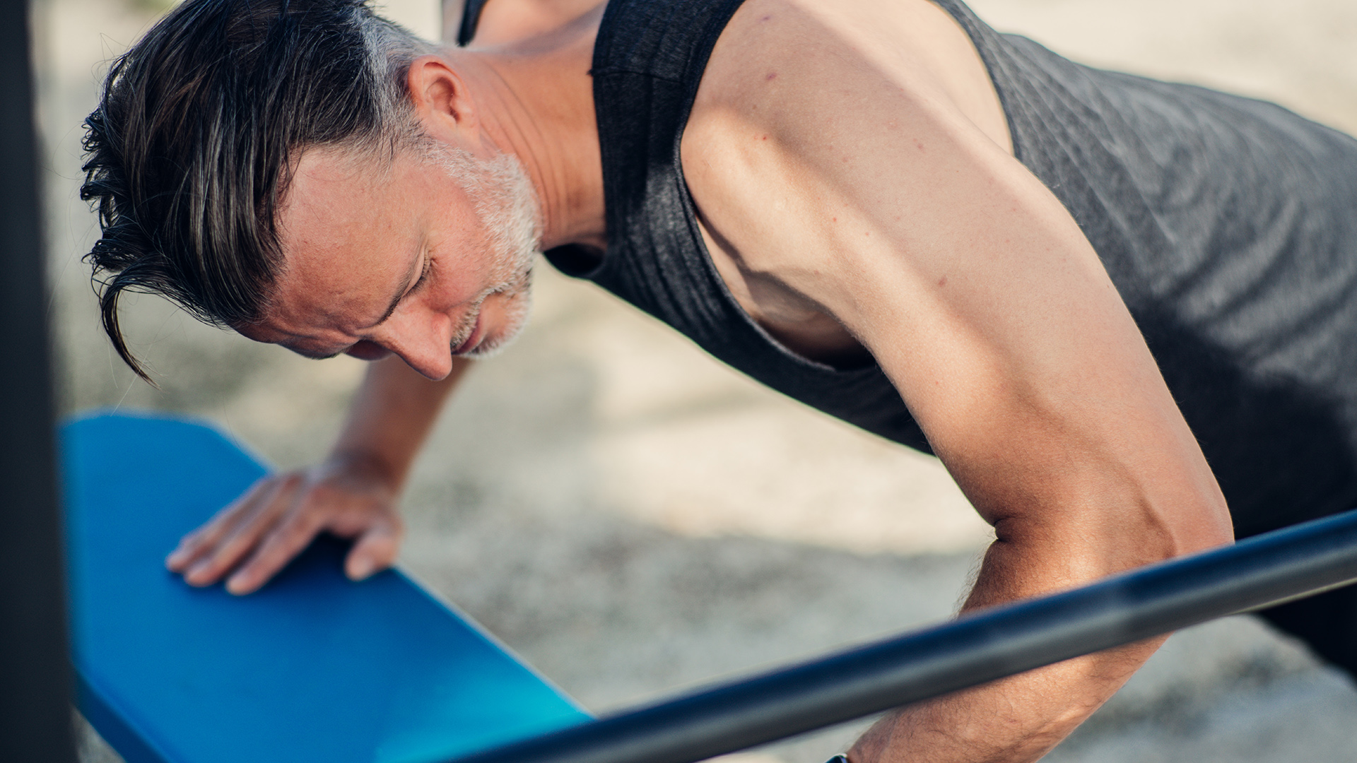 Man doing push ups outdoor while looking at his smartwatch to check data and pulse.