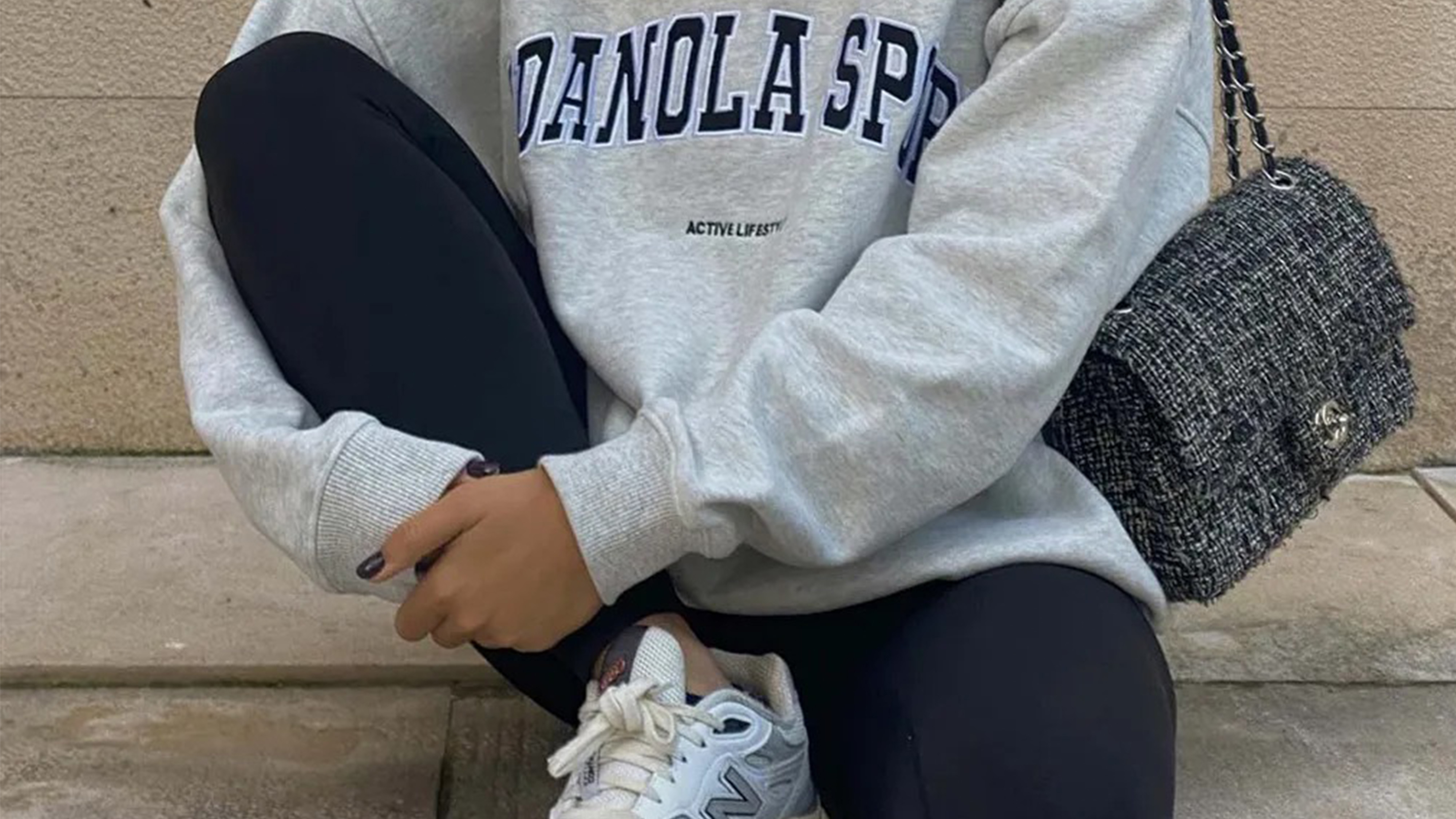 Woman wearing leggings with New Balance sneakers and a gray crewneck.
