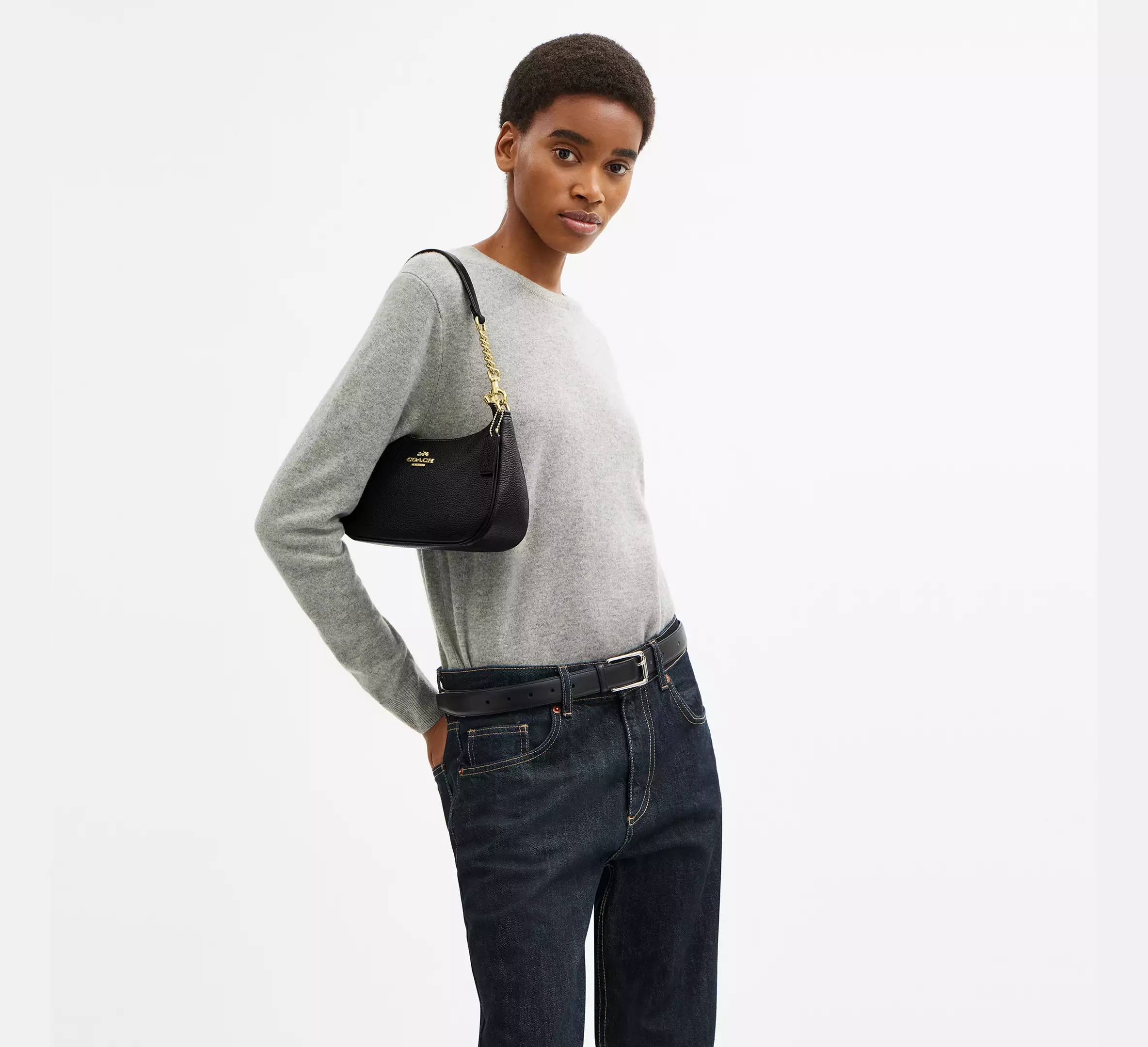 model carrying a black coach Teri bag wearing a gray sweater and blue jeans
