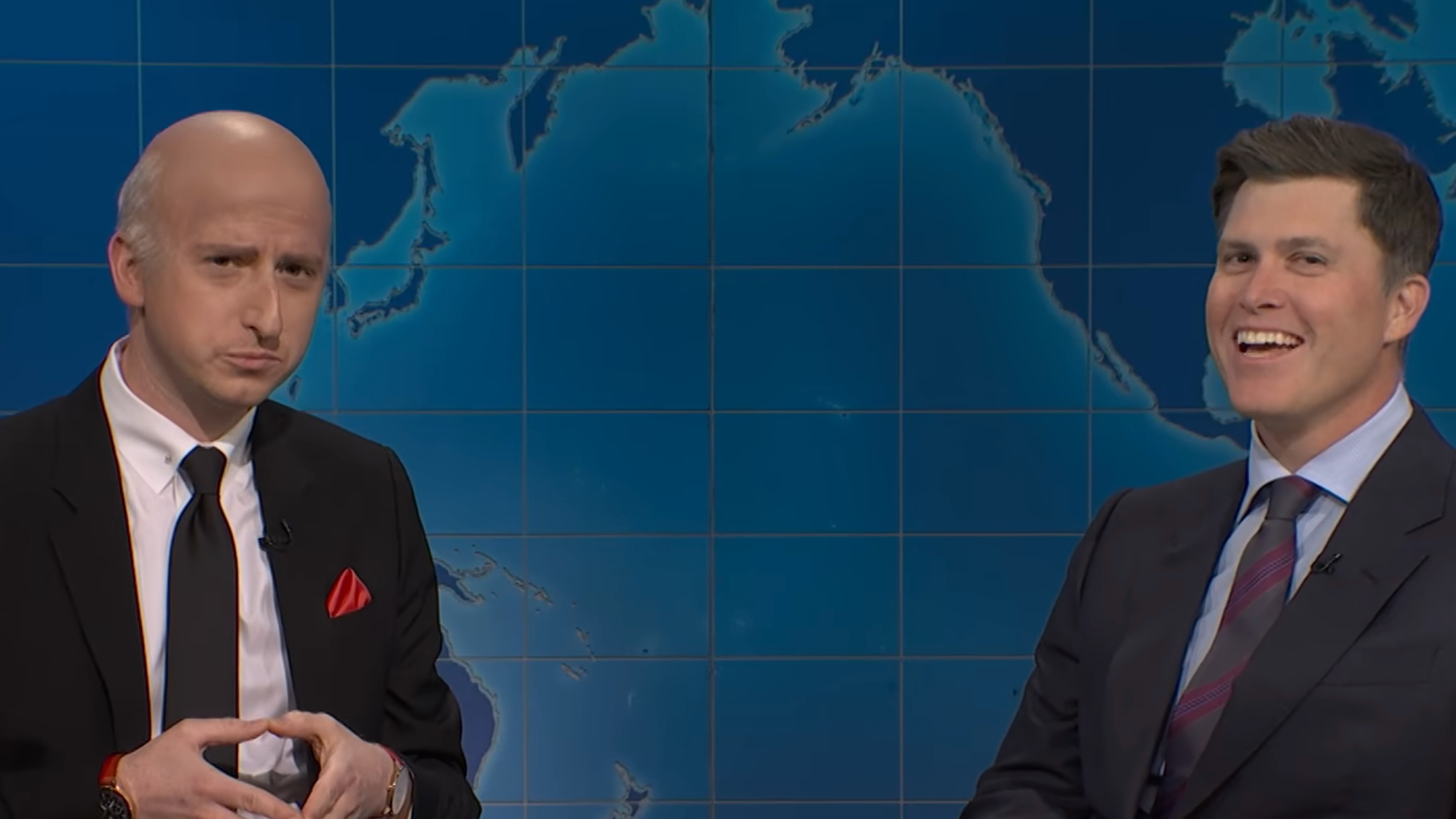 Colin Jost laughs while talking to James Austin Johnson dressed as Mr. Wonderful on Weekend Update.