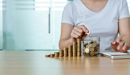 Woman moving coins from stacks into a glass jar