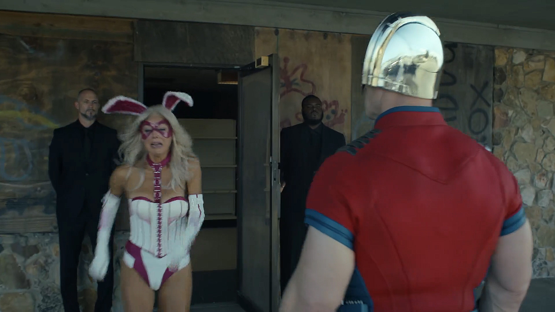 An upset woman wearing a white rabbit costume walking past Chris Smith in Peacemaker season 2 episode 1