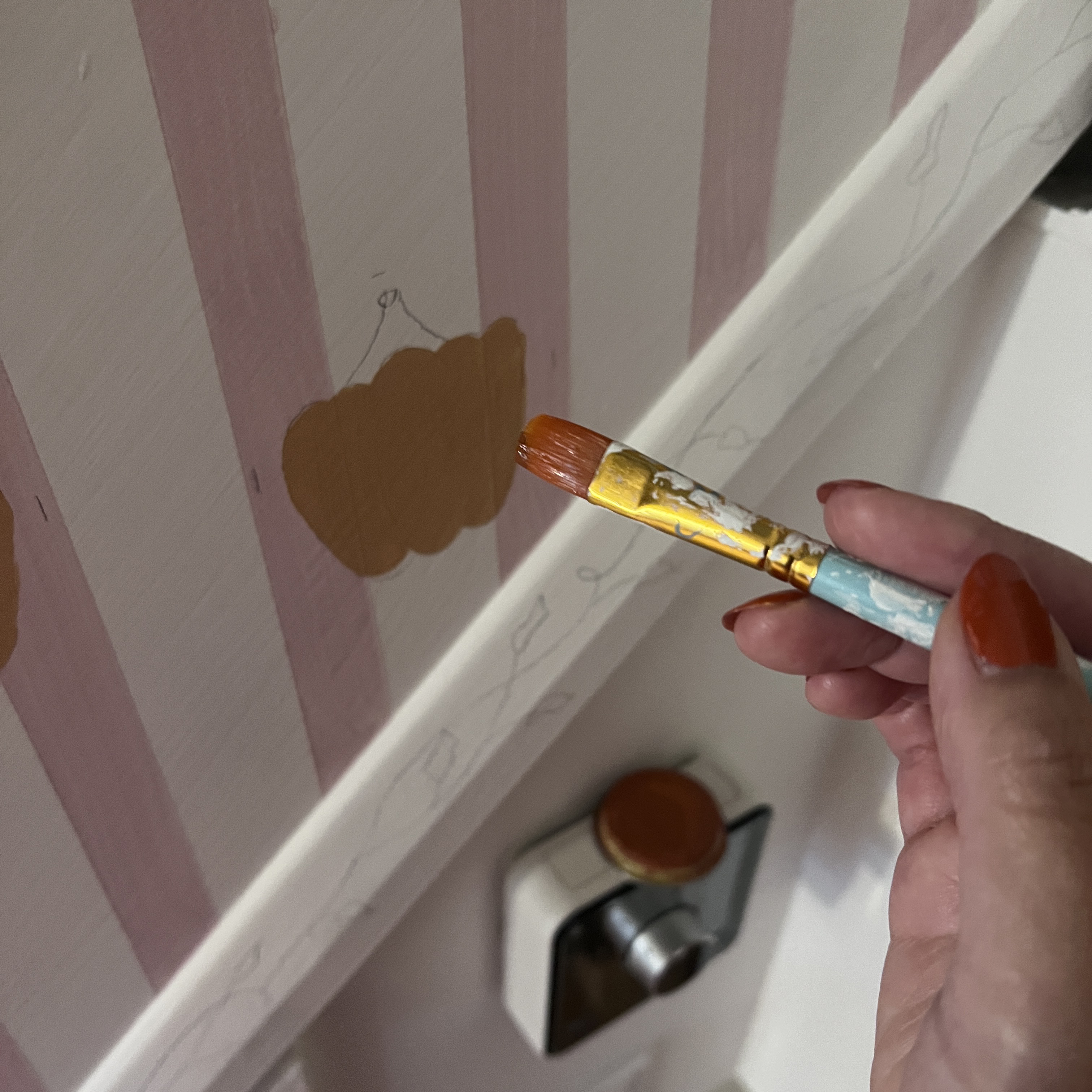 painting a pumpkin motif on a striped wall by hand