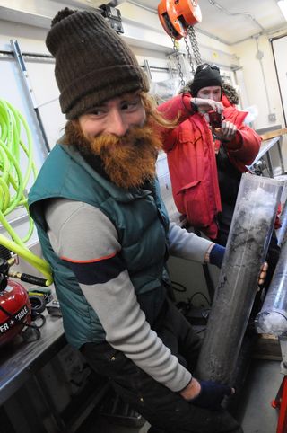 Timothy Hodson, a doctoral student at Northern Illinois University, holds a core of sediment drilled from Subglacial Lake Whillans, a lake buried deep beneath the West Antarctic Ice Sheet.