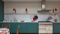 a large kitchen with teal cabinetry, a white oven, red wall sconces, and a white marble backsplash