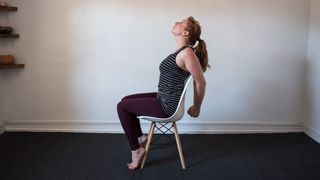 desk exercises: woman sat down, reaching behind to stretch the chest out