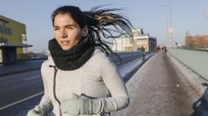 Woman running wearing thick jumper, gaiter and gloves