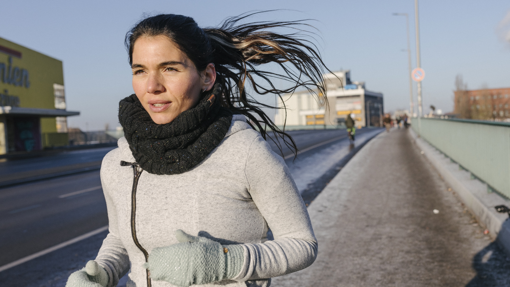Woman running wearing thick jumper, gaiter and gloves
