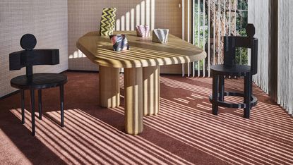 contemporary dining table and black chairs on a soft red carpet