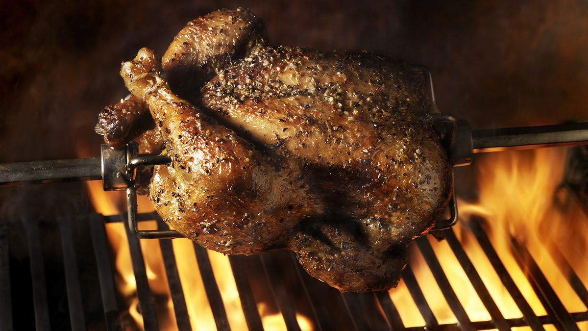 A seasoned turkey roasting on spit over a fire