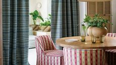 a dining room with striped chairs and curtains, with glasses and a vase on the table