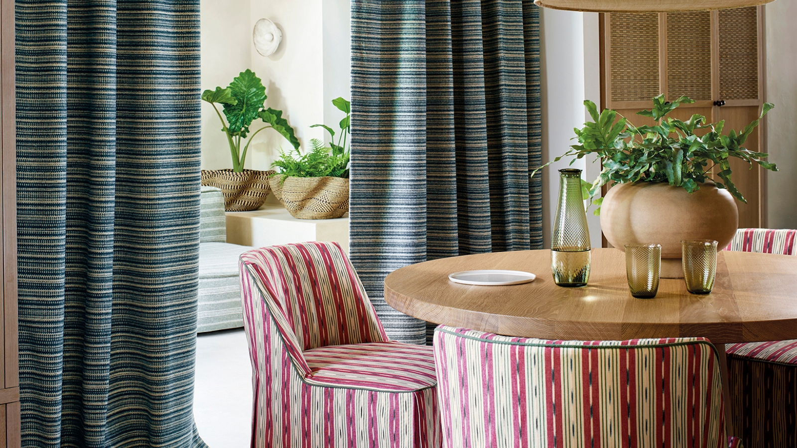 a dining room with striped chairs and curtains, with glasses and a vase on the table