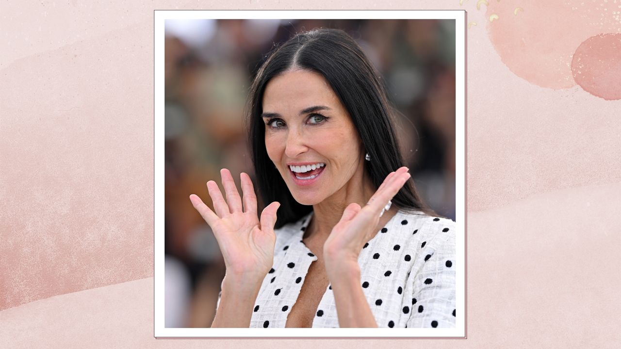 Demi Moore is pictured wearing a black and white polka dot dress and waving her hands whilst attending the &quot;The Substance&quot; Photocall at the 77th annual Cannes Film Festival at Palais des Festivals on May 20, 2024 in Cannes, France/ in a pink watercolour paint-style template