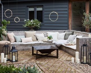 Outdoor summer seating area with a metal fire pit, lanterns and hanging lights
