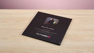 The Mixbook photo book sits on a light wooden surface with the back cover facing upwards.