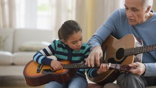 Best guitars for kids: Grandad and granddaughter play guitar together