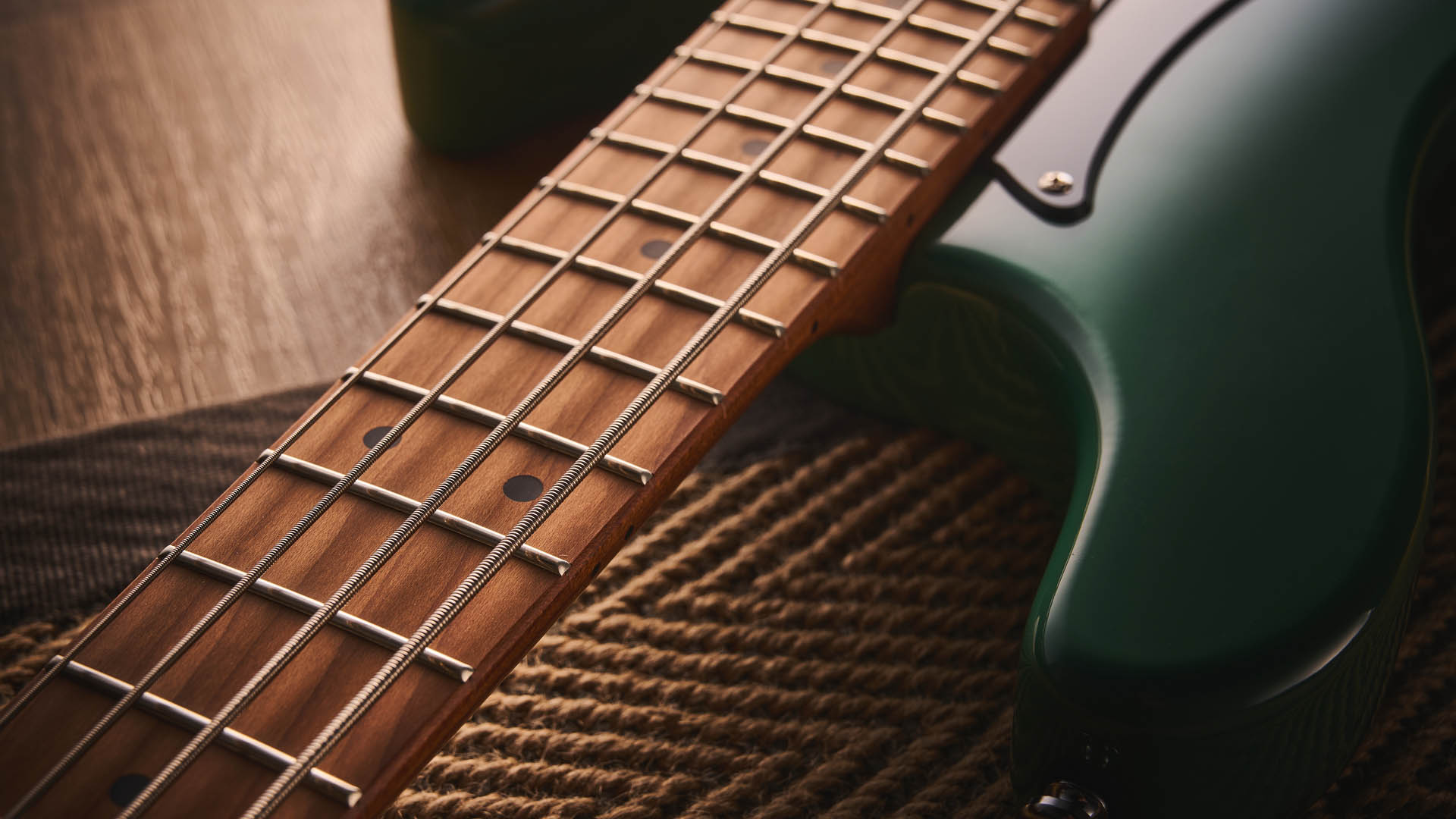 The Cort GB-Short Scale Bass finished in green, photographed against a light wooden floor and rug.