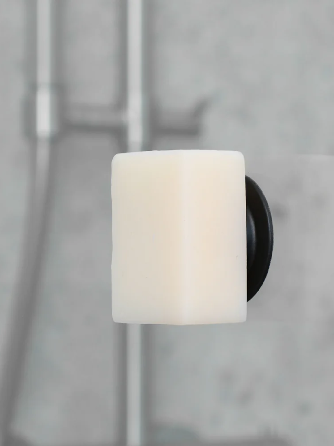 A black magnetic soap holder with a white bar of soap