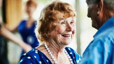 Smiling senior woman looking at husband while dancing in ballroom