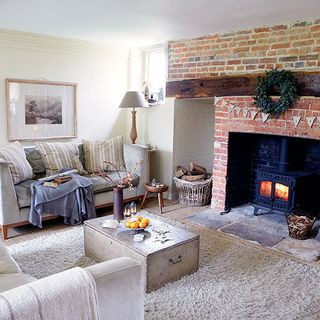 living room with white wall brick wall at fire place and grey sofa with cushions