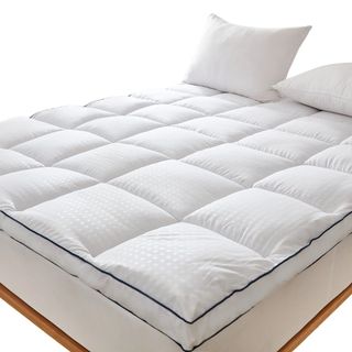 A white padded mattress topper on a bed with white pillows