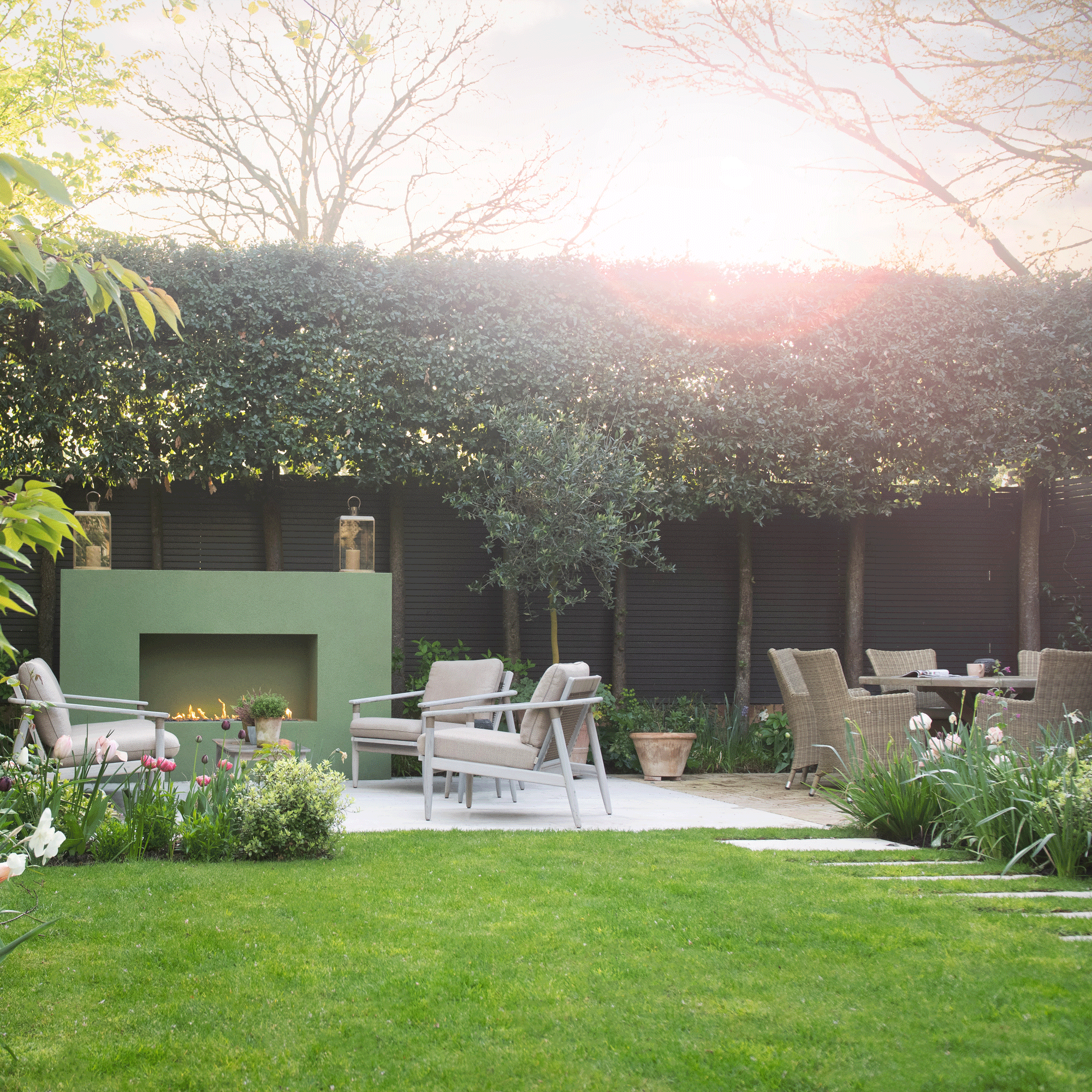a garden with a patio area and large green outdoor fireplace and seating in front