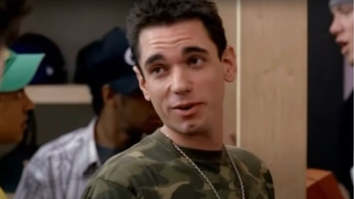 DJ AM wearing a camo t-shirt while talking in frontt of some cardboard boxes in Entourage.