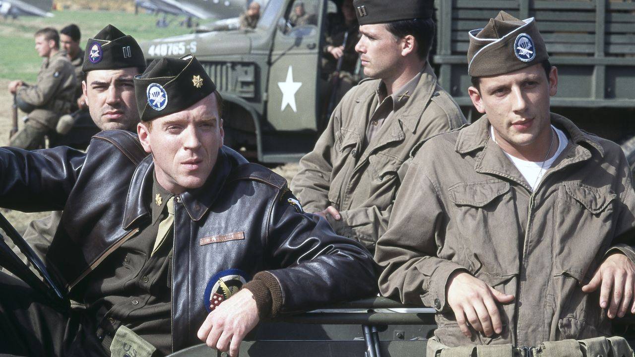 Members of Easy Company sitting in, and standing by, a car in Band of Brothers
