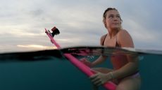Female surfer sitting on a surfboard half underwater