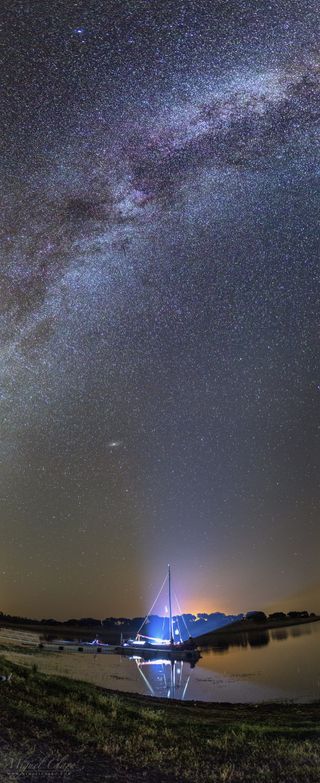 Visible below two galaxies, our Milky Way and the Andromeda Galaxy, is an old Dutch Westlander sailboat named Sem Fim. Thus vertical panorama was captured from the Dark Sky Alqueva Reserve in Portugal.