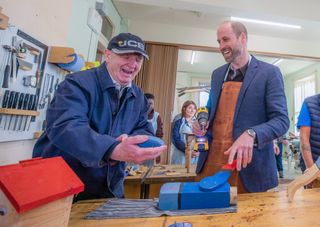 Prince William laughing and interacting with a senior citizen at a table