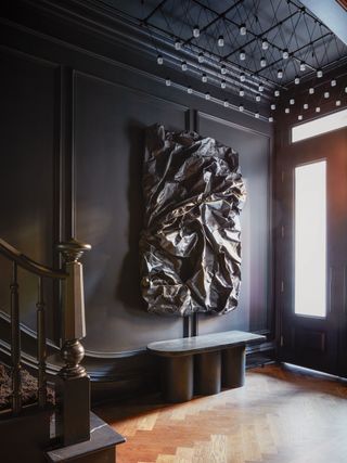 a dark entryway with crumpled wall art