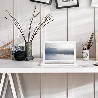 home office area with white wall and table with laptop and stationary flower pot