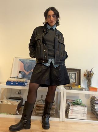 Lucia Tonelli wearing a black top, blue button down top, black jacket, black skirt, tights and moto boots