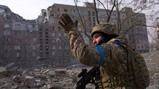 A Ukrainian soldier in front of a ruined building in Mariupol, Ukraine, taken from the documentary film "20 Days in Mariupol"