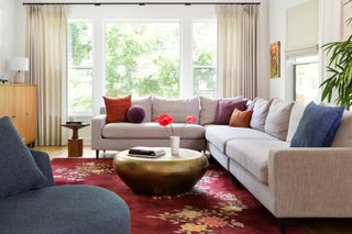 A living room with a large grey corner sofa, Persian-style carpet and brass coffee table