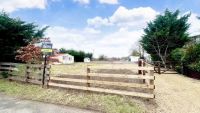 A plot with a wooden gate and gravelled driveway