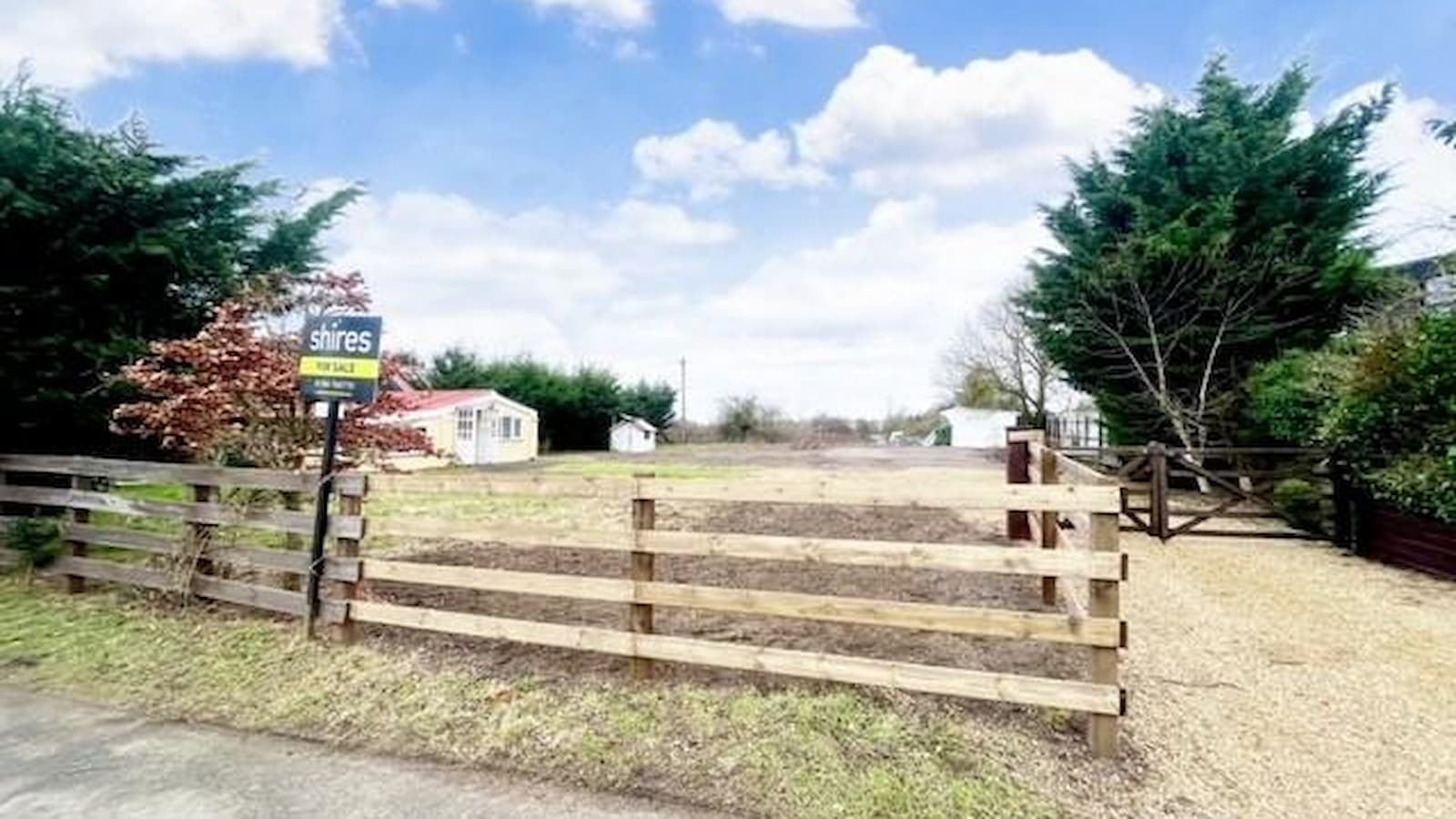 A plot with a wooden gate and gravelled driveway