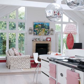 Large white kitchen with pink aga and mirror ball lights