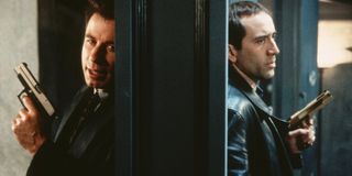 John Travolta and Nicolas Cage talking through a doorway, guns drawn, in Face/Off