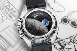 Astronaut Snoopy orbits the moon aboard an Apollo command and service module on the animated caseback of the 50th anniversary "Silver Snoopy Award" Speedmaster chronograph.