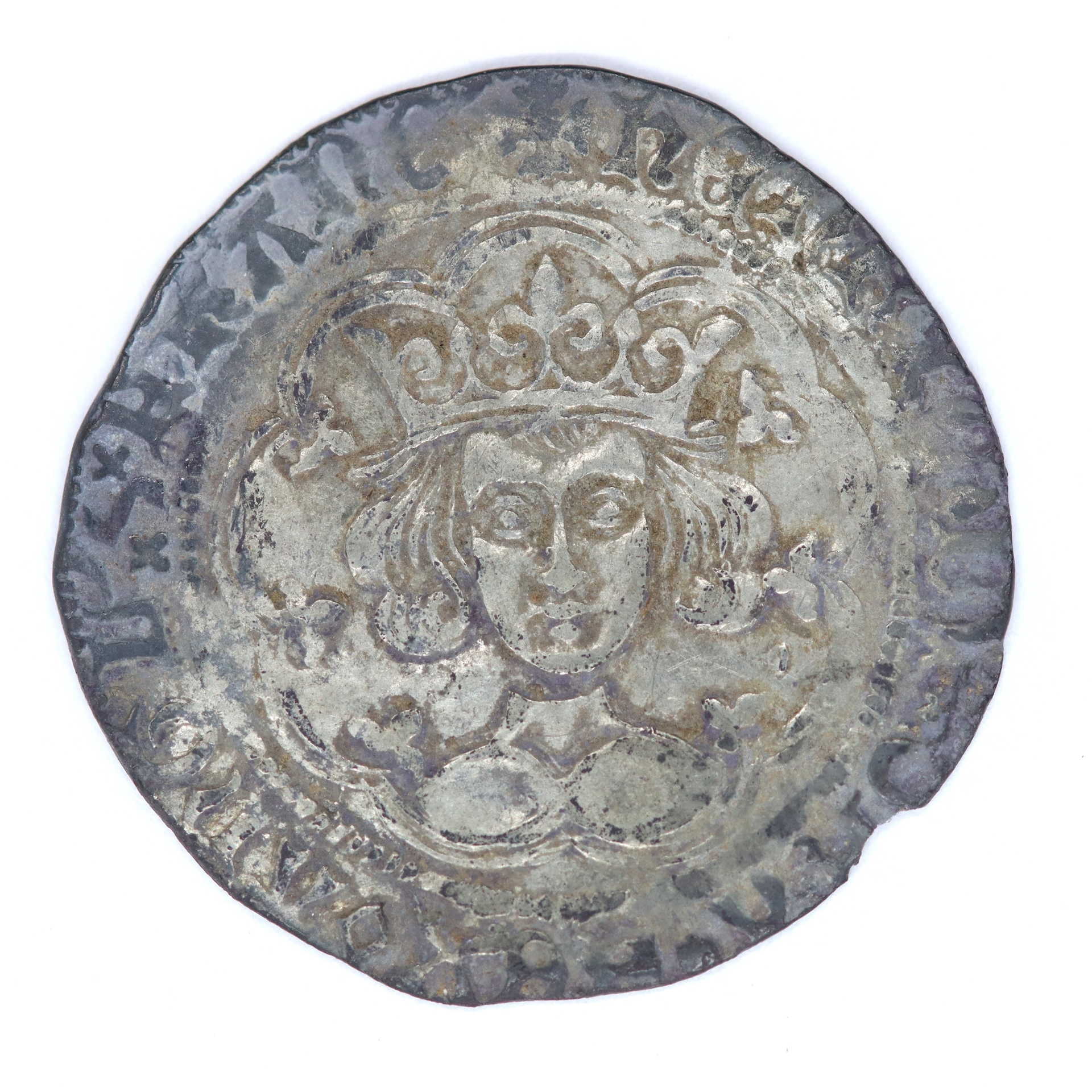 A closeup of a silver coin with a king's image on it