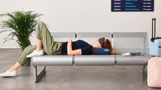 A woman lying on a neck pillow in the airport