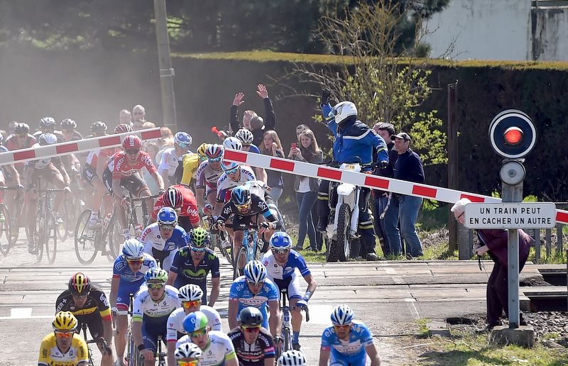 Riders squeeze under the quickly closing barriers at Paris-Roubaix