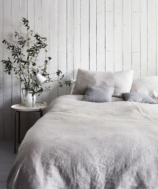 A white bedroom idea with whitewashed wooden panels on the walls