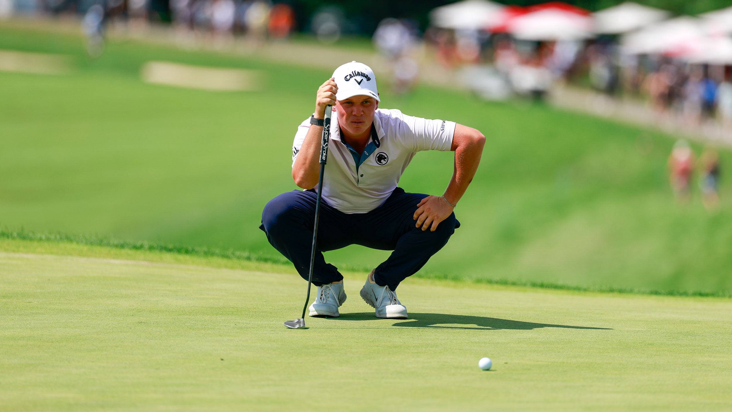 Caleb Surratt crouches down behind a putt during LIV Golf Indianapolis 2026