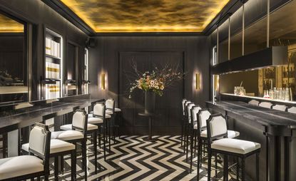 Hexagone Adjacent bar counters with white barstools, black and white zigzag striped floor tiles with dark wood interior